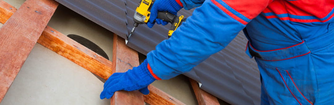 A worker installing corrugated metal roofing